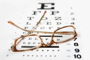 Picture of a pair of glasses sitting on top of an eye exam chart.